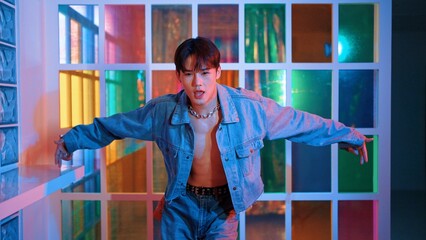 Close up of asian performer with sun glasses moving freestyle dance while looking at camera at nightclub. Happy street dancer dancing and show footstep with colorful bright neon light. Regalement.