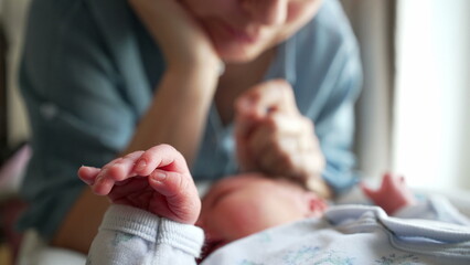 Soft focus on newborn's tiny hand while parent gazes lovingly, illustrating early moments of bonding and deep emotional connection in parenthood. Symbolizes protection and care