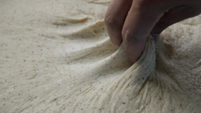 A baker's hands stretching gluten sourdough, slow motion
