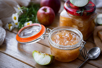 Apple jam in a glass jar on a wooden table. Sweet confiture of apples in a glass jar. Close-up