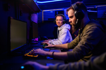Small group of gamers sitting in cybercafe and playing online games.