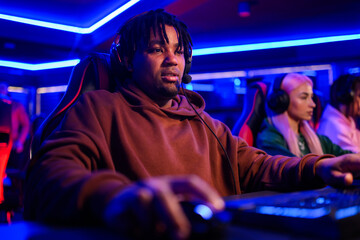 Focused interracial gamer with headset participating in mmo game.