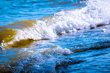 Wave of Water Splashes & Breaks at the Lake Shoreline in Blues & Tans