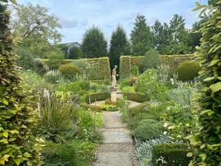 Plouëc-du-Trieux, France, July 24, 2024: Gardens Kerfouler. A classical garden scene featuring lush greenery and a central statue of Helen of Troy, framed by carefully trimmed hedges and pathways