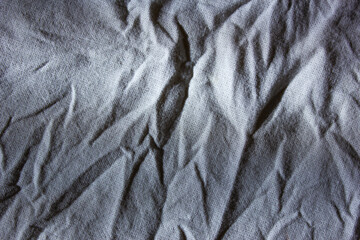 Wrinkled, crumpled fabric on sunbeam, background, texture. Crumpled blue cotton, creased fabric.