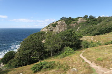 Ein Wanderweg schl&auml;ngelt sich von M&ouml;lle &uuml;ber den Kullaberg zur Spitze, dem Leuchtturm Kullens fyr. Er ist Teil des Wanderwegs Skaneleden. Unten branden Wellen des &Ouml;resunds an der Felsk&uuml;ste im Sommer. 