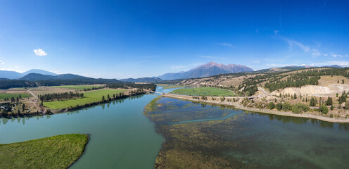 Scenic Panorama of Tranquil River and Lush Green Fields in BC, Canada on a Clear Day