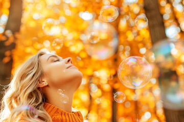 Fototapeta premium A woman with long hair smiles as she stands amid golden autumn foliage, surrounded by floating soap bubbles, capturing the essence of a peaceful fall afternoon.