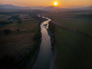 Forest fire smoke sunset shot overlooking a riving flowing through agriculture fields overlooking distant mountains in North America.