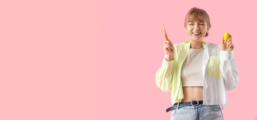 Happy female artist holding paint and brush on pink background with space for text