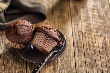 Sweet chocolate muffin cakes on plate on wooden table.