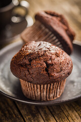 Sweet chocolate muffin cakes on plate on wooden table.