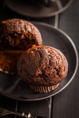 Sweet chocolate muffin cakes on plate on wooden table.