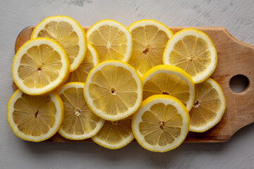 Organic Yellow Sliced Lemons on a Rustic Wooden Board, top view.
