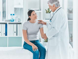 Obraz premium Doctor, woman and handshake in office for support, empathy and friendly service in healthcare. Mature gynecologist, patient and gesture in practice for trust, consultation and assurance in clinic