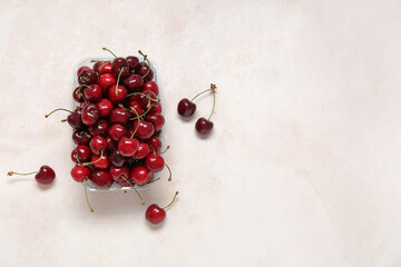 Plastic container with fresh cherry on white background