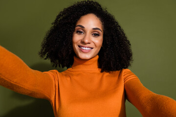 Photo of good mood gorgeous woman with curly hairdo dressed orange turtleneck making selfie isolated on dark khaki color background