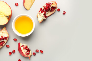 Bowl of honey with pomegranate and apples for Rosh Hashanah celebration (Jewish New Year) on grey background