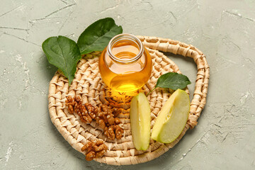 Jar of sweet honey with apple and walnut on grey background