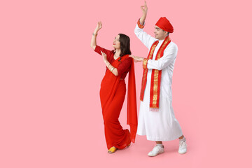 Beautiful Indian couple dancing on pink background