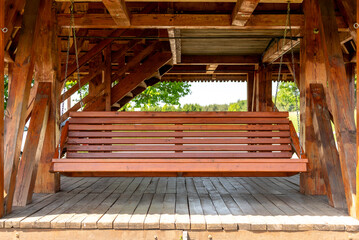 Wooden garden brown color swing in summer.Rest on a country plot. Wooden furniture for the garden.