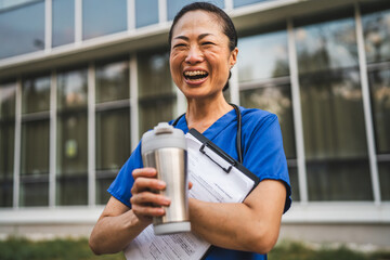 mature japanese doctor stand in front the building and hold clipboard