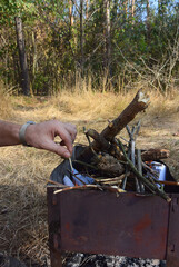 A man lights up a grill in nature.