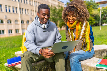 Multiethnic students studying together with a laptop sitting on campus