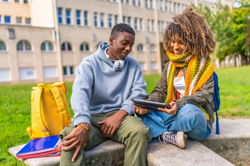 Multiethnic college students sitting outdoors and using digital tablet