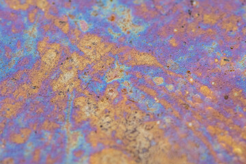 Colorful oil slick patterns in a small water puddle