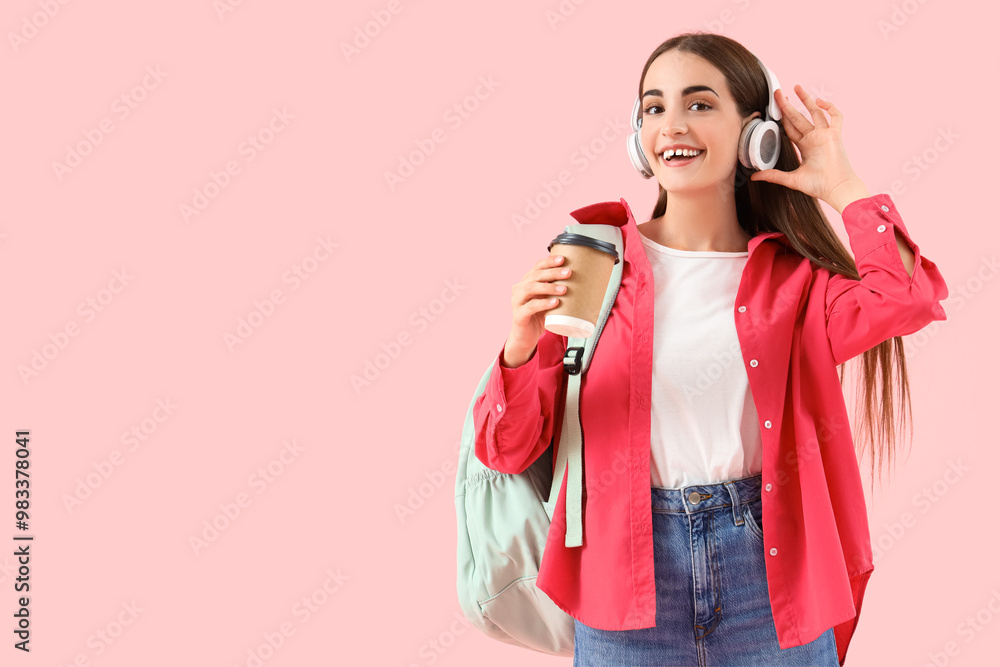 Poster Happy female student in headphones with backpack and cup of coffee on pink background