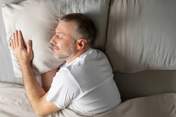 Obraz premium Calm middle aged man sleeping on bed, on soft pillow under duvet in bedroom interior, enjoying healthy sleep, profile shot, top view
