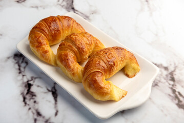 Fresh sweet and salty golden butter croissants alone and filled with ham and cheese on white sheet