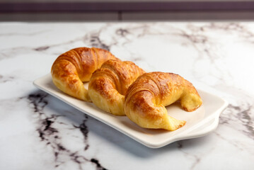 Fresh sweet and salty golden butter croissants alone and filled with ham and cheese on white sheet