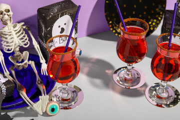 Glasses of tasty cocktails and decorations prepared for Halloween on grey table