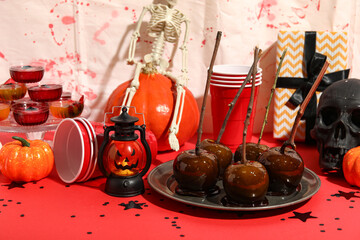 Sweet treats, plastic cups and decorations for Halloween party on red table