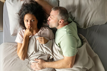 Problems in bed because of alcohol. Woman close nose and refusing kiss her man in bed because of...