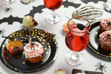 Glass of tasty cocktail, sweet treats and decorations on light background