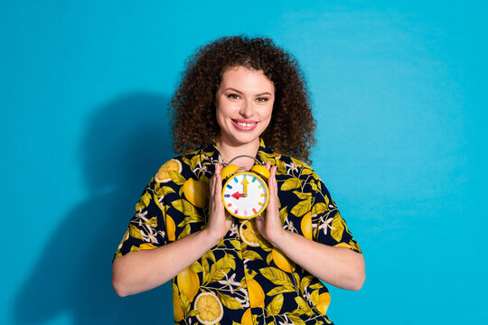 Photo of lovely cute cheerful girl wear trendy print clothes hold alarm clock isolated on blue color background