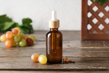 Bottle of cosmetic grape seed oil on wooden table