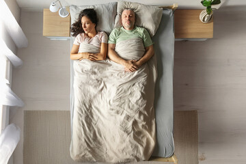Upset thoughtful young woman lying on bed near sleeping husband, lady think about problems, suffers...