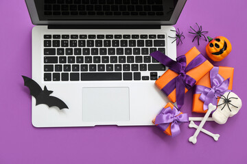 Composition with modern laptop, gifts and decorations for Halloween on purple background