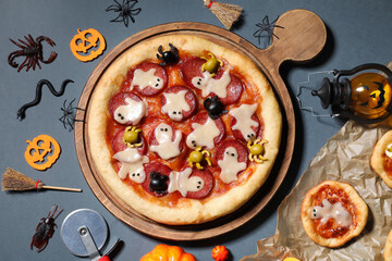 Composition with tasty Halloween pizzas, cutter and decorations on dark background