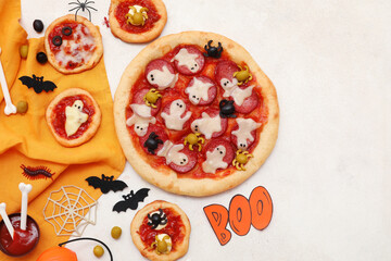 Composition with tasty Halloween pizzas, tomato sauce and decorations on light background