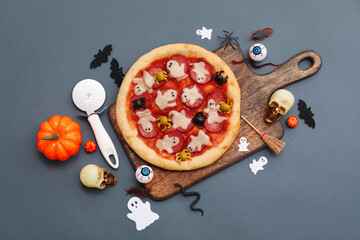 Composition with tasty Halloween pizza, cutter and decorations on dark background