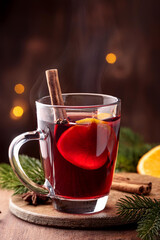 Mulled wine with orange and cinnamon in a glass glass. Hot wine with cinnamon. Warming winter drink with orange and cinnamon. Hot tea with orange and cinnamon.