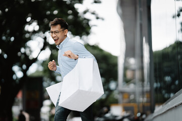 Shopping Spree Success: Exuberant young man revels in retail therapy, dashing through the city with...