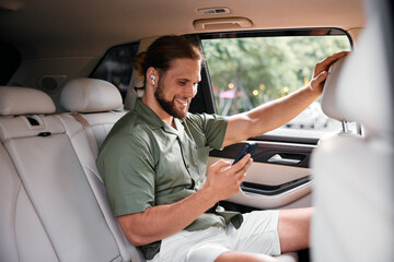 Young man enjoying music on smartphone in a car interior with modern design
