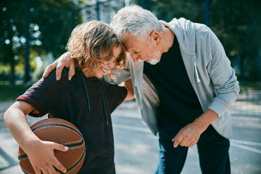 Grandfather teaching grandson basketball outdoors