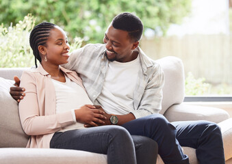 Obraz premium Black couple, pregnant and hand on stomach for support, love and feeling baby kick in home. Future parents, happy and touch belly in living room for growth, maternity and commitment in relationship